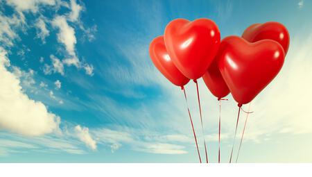 Group of heart shaped red air baloon on blue sky with clouds. Valentines day and romance concept - Stock Image