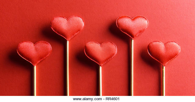 Red textile hearts on wooden sticks closeup. Valentines day background, creative texture and love concept - Stock Image