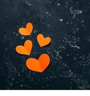 Valentine's Day. Orange paper hearts on black stone grunge background flat lay. Top view - Stock Image