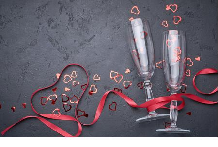 Valentine's day greeting card with champagne glasses and candy hearts on stone background. Top view with space for your greetings. Flat lay - Stock Image
