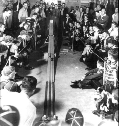 Vintage pinewood derby race in a crowd of spectators.