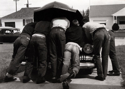 Vintage group of men working on car under hood.