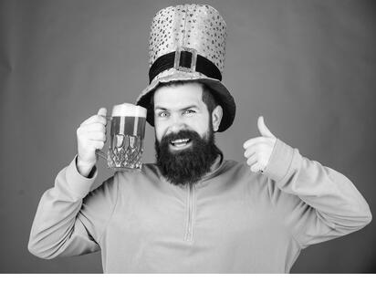 Hip hip hooray its st pattys day. Leprechaun hipster holding beer mug. Bearded man toasting to saint patrick. Irish man with beard giving thumbs up to green beer. Celebrating saint patricks day. - Stock Image