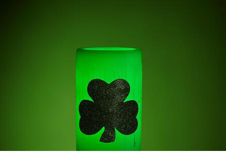 Glowing green wax candle for St. Patrick's Day Celebration - Stock Image
