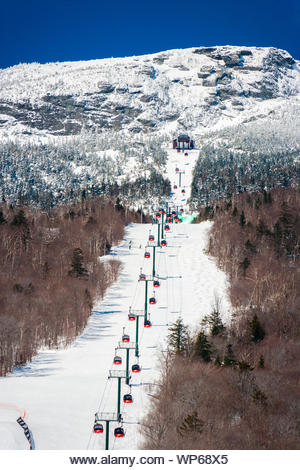 Stowe, VT, USA - Mar 17, 2005: The gondola lift to the top of the Stowe Mountain Resort over a green dyed waterfall for St. Patricks Day - Stock Image