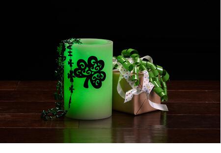 Glowing green wax candle and gift for St. Patrick's Day Celebration - Stock Image