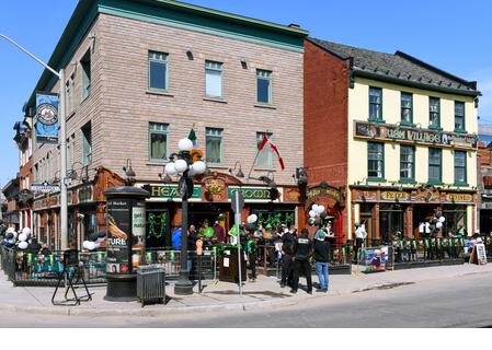 Ottawa, Canada – March 17, 2021: A much smaller crowd than usual, because of Covid-19 restrictions, celebrates St. Patrick’s Day at the popular Irish Pub the Heart and Crown.  Warm weather made patio seating possible. - Stock Image