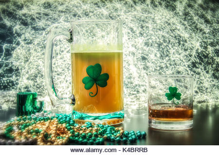 St Patricks Day themed items, large mug of beer, small glass of Irish Whiskey, beads, clovers and lights. - Stock Image