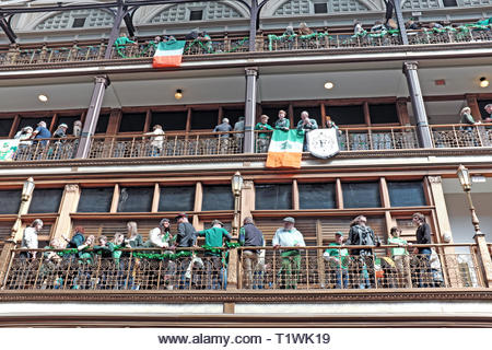 St. Patrick's Day celebrants enjoy the organic indoor 'street' party in the Arcade, a historic indoor mall with hotel in downtown Cleveland, Ohio, USA. - Stock Image